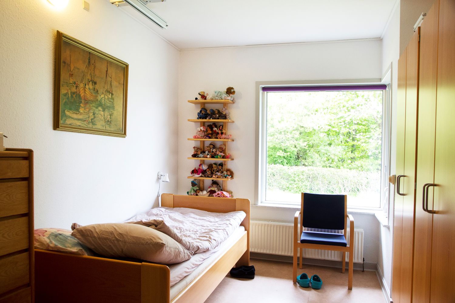 Et værelse med en seng og ved siden af sengen står der en stol foran et vindue.