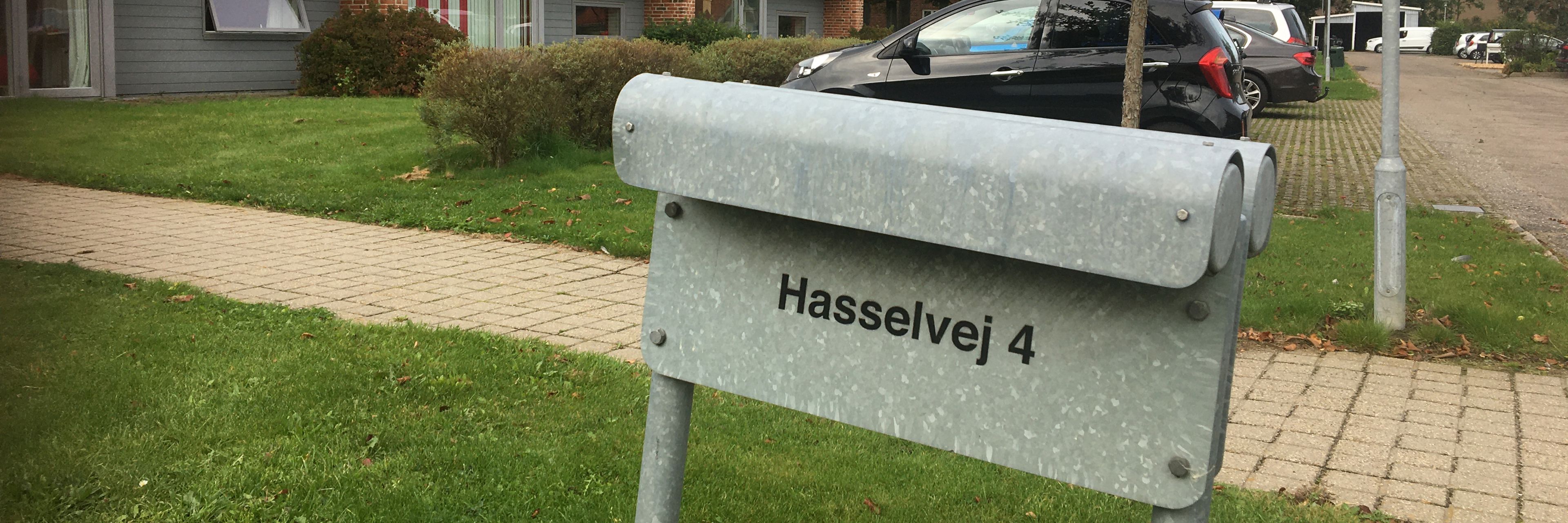 Udenfor ved indgangen står der et gråt skilt hvor der står Hasselvej 4.