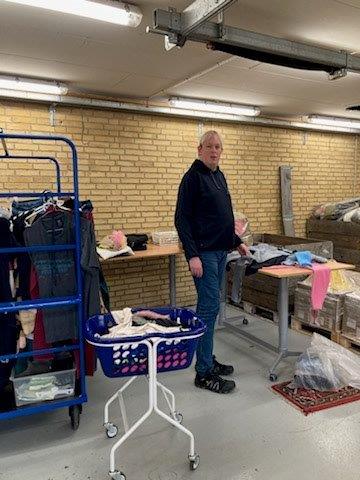 Borger står og er ved at sortere noget tøj der skal sættes til salg i 2nd Hand butikken. 