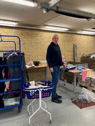 Borger står og er ved at sortere noget tøj der skal sættes til salg i 2nd Hand butikken.