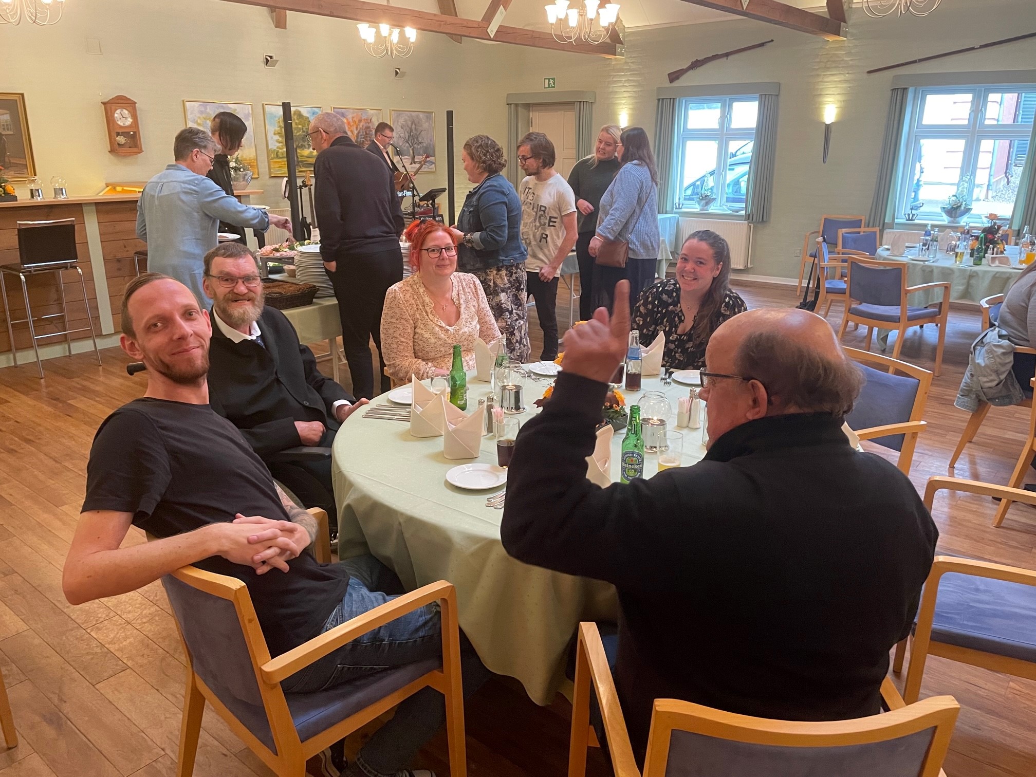 Borgere og personale er på Agerskov kro, der er dækket fint op med lysegrønne duge og servietter foldet fint, så de kan stå op, alle ser glade ud