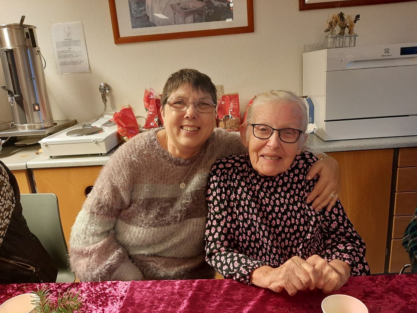 To borgere sidder tæt sammen ved et bord. Den ene har sin arm om skuldrene på den anden.