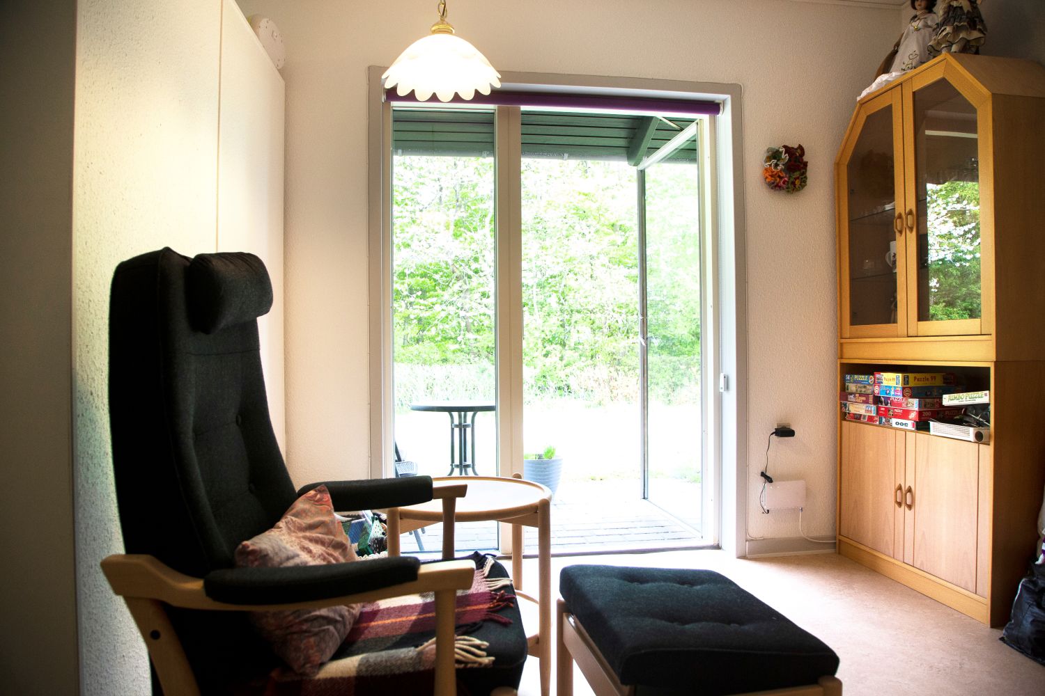 Foran i billedet står der en lænestol med skammel og der står en reol.