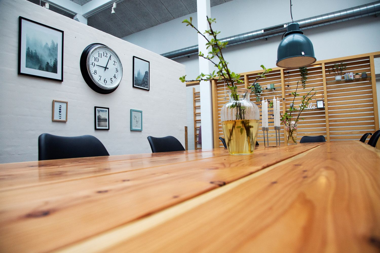 Lakeret plankebord med vaser med grønne grene i og en lysestage med fire lange lys i