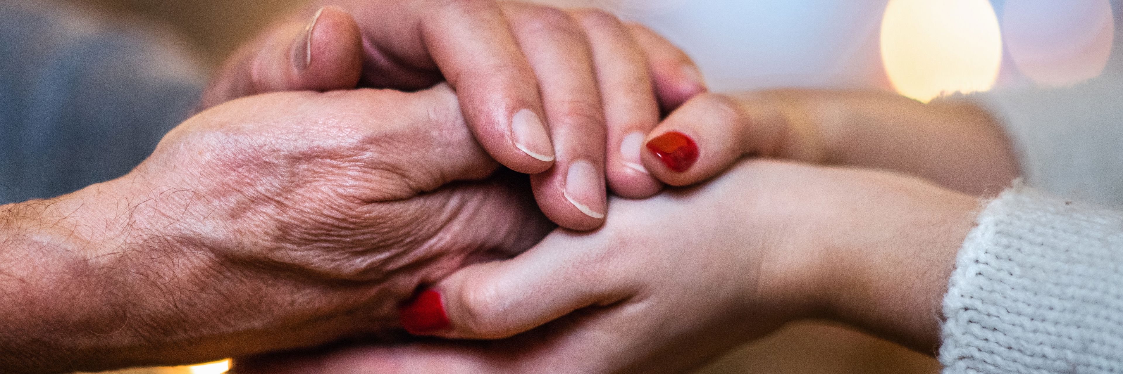 Billede af to personer der holder hinanden i hånden. Den ene person er ældre og den anden ung.