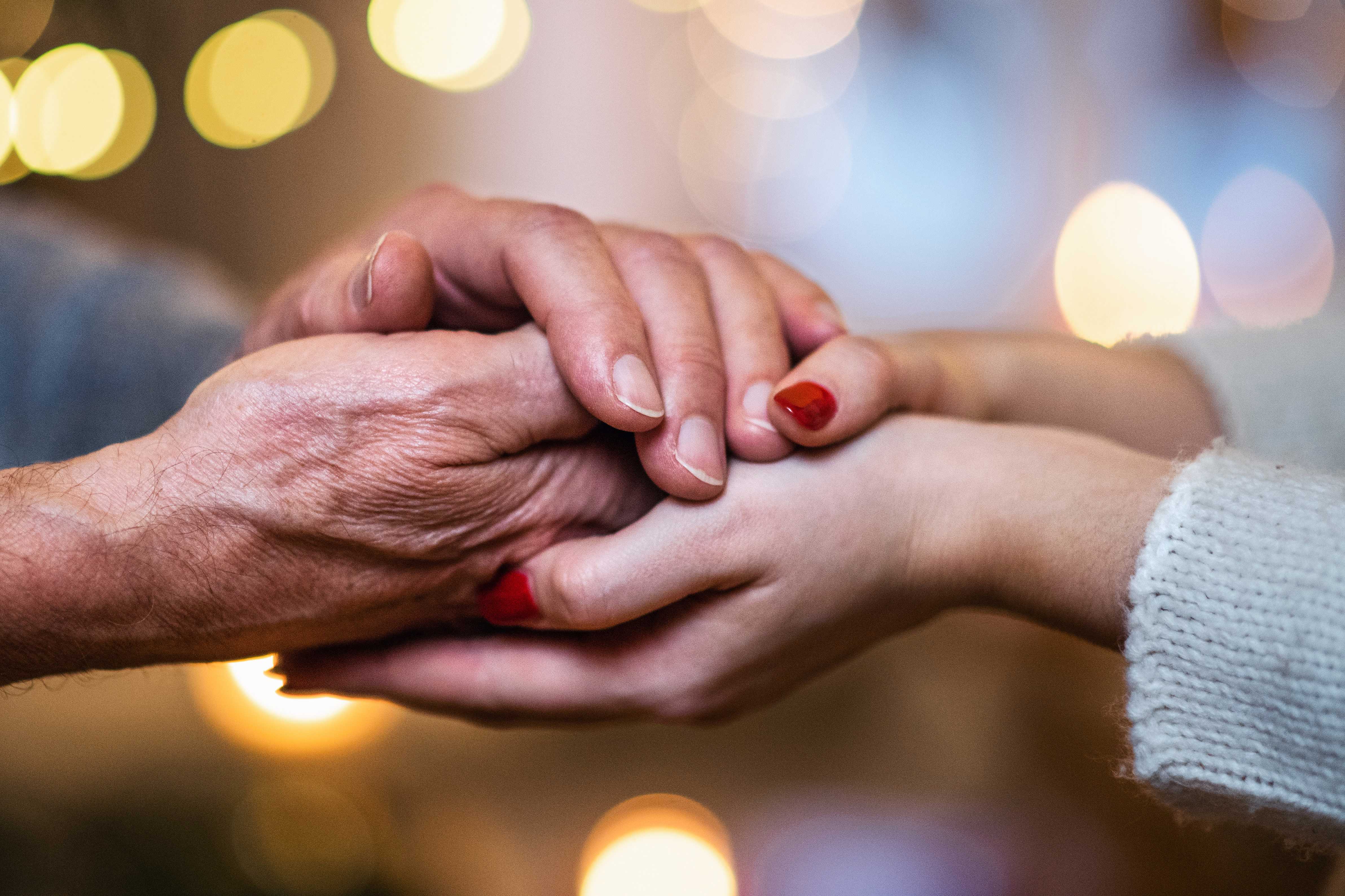 Billede af to personer der holder hinanden i hånden. Den ene person er ældre og den anden ung.