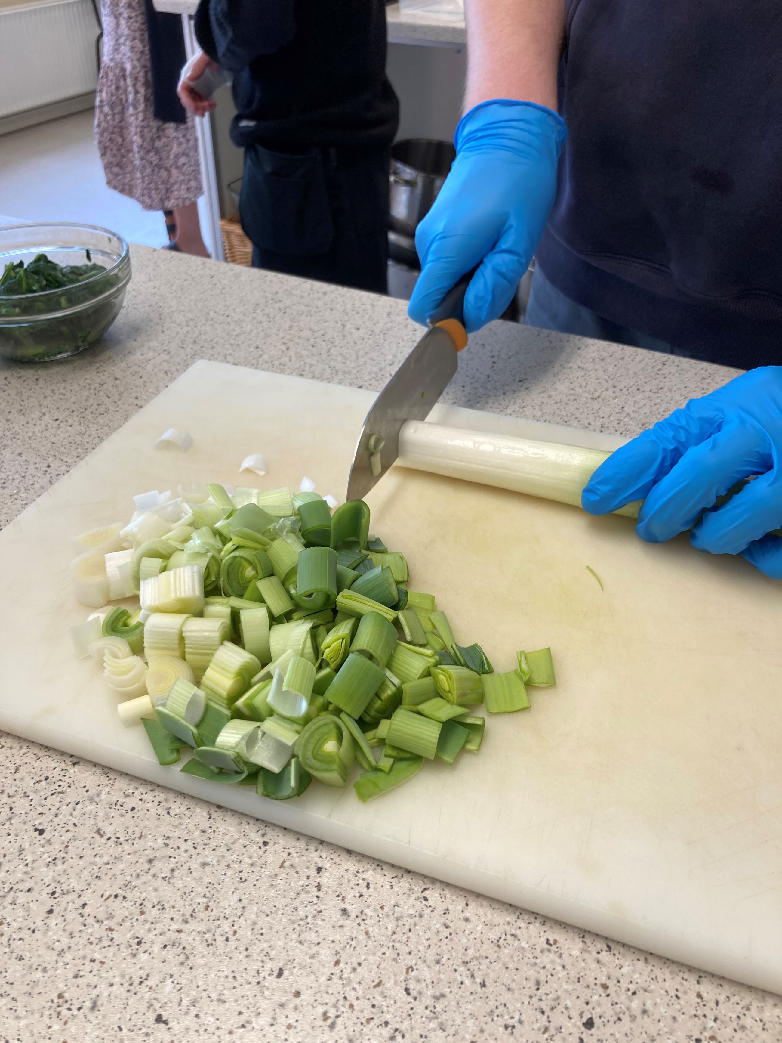 Der bliver skåret porrer ud til maden, der bliver brugt handsker.