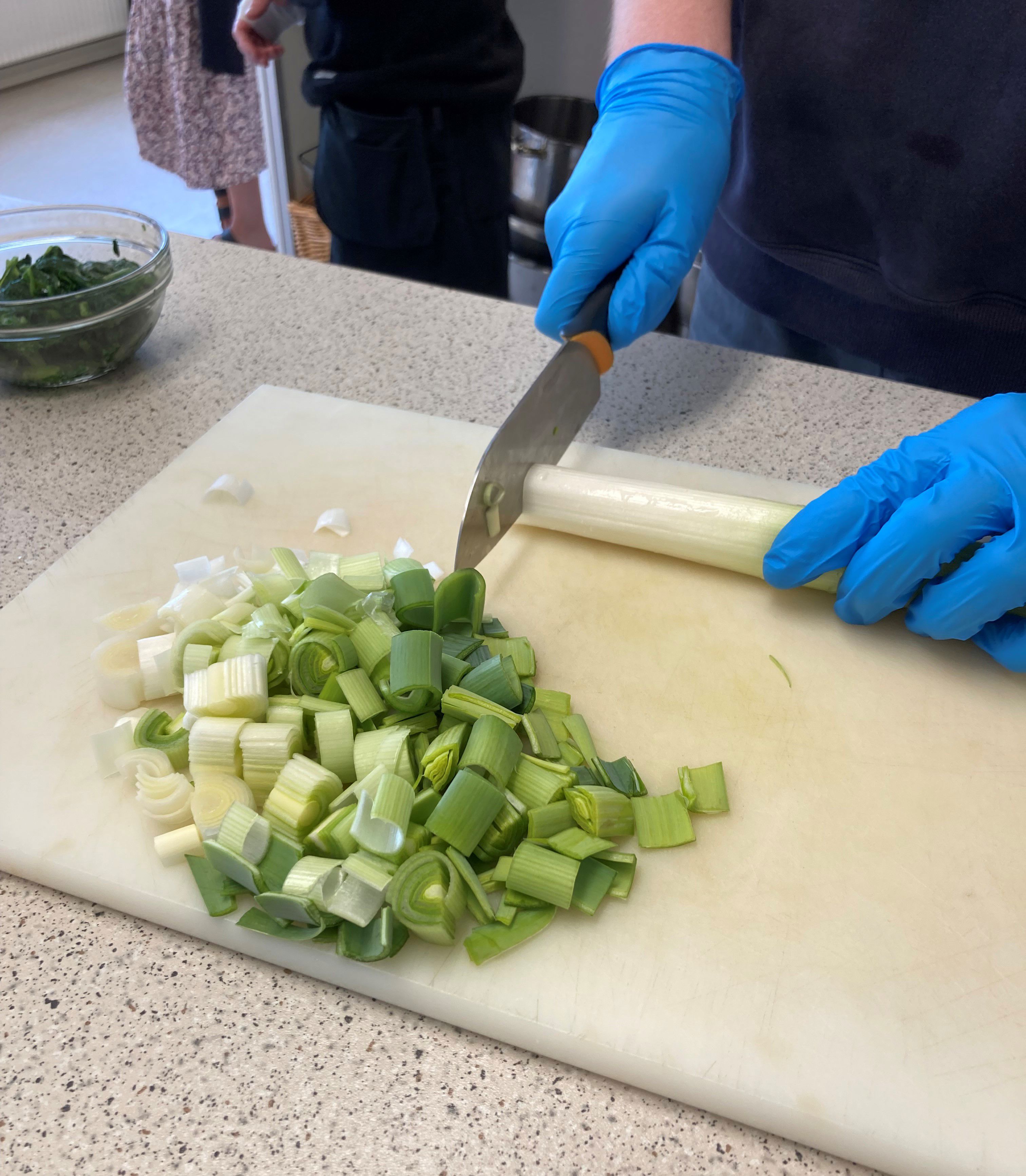 Der bliver skåret porrer ud til maden, der bliver brugt handsker.