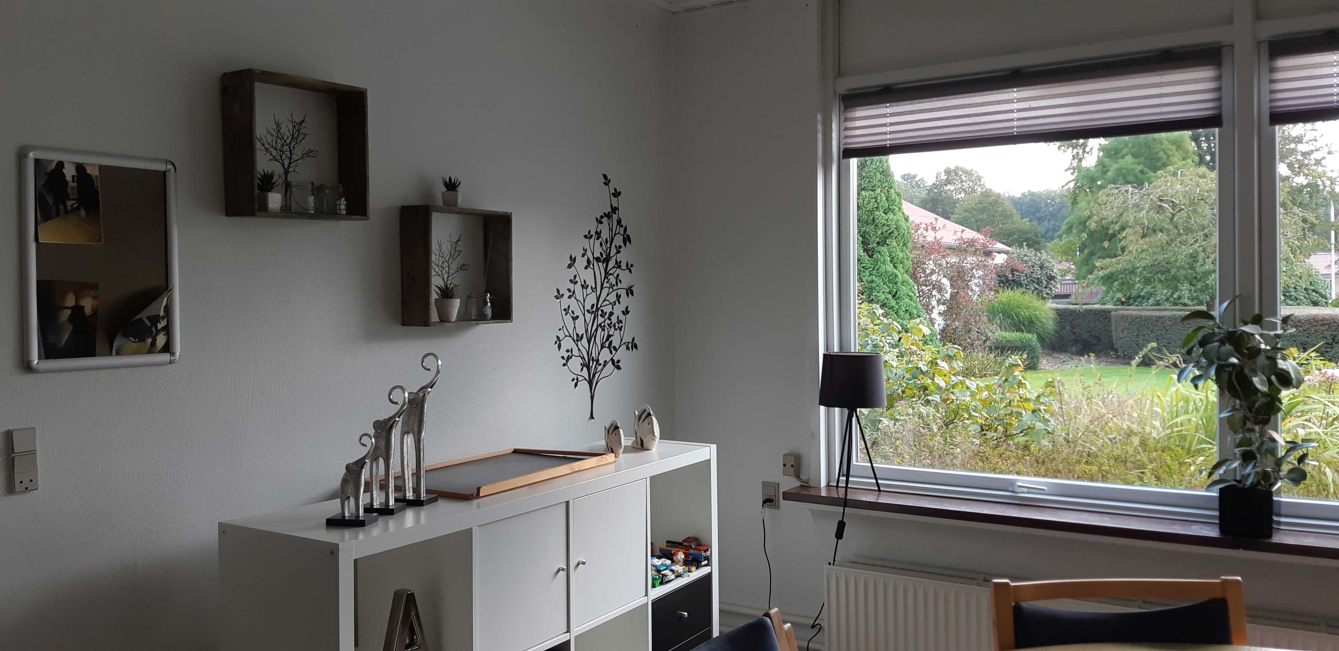 Leglighed hvor der en reol, et bord med stole og billeder på væggen