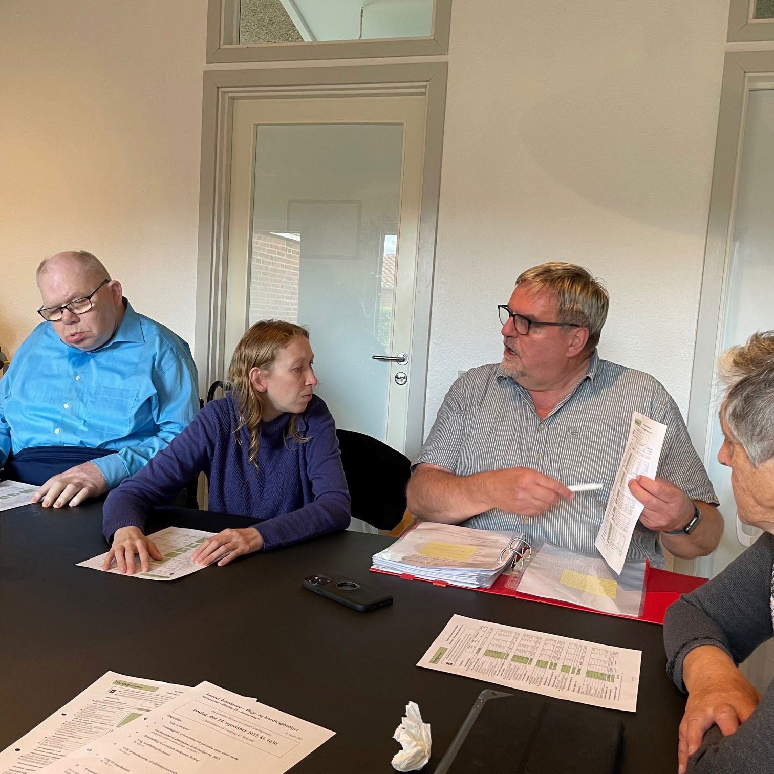 Medarbejder fra Boligkontoret sidder og gennemgår budgettet med personerne omkring bordet.