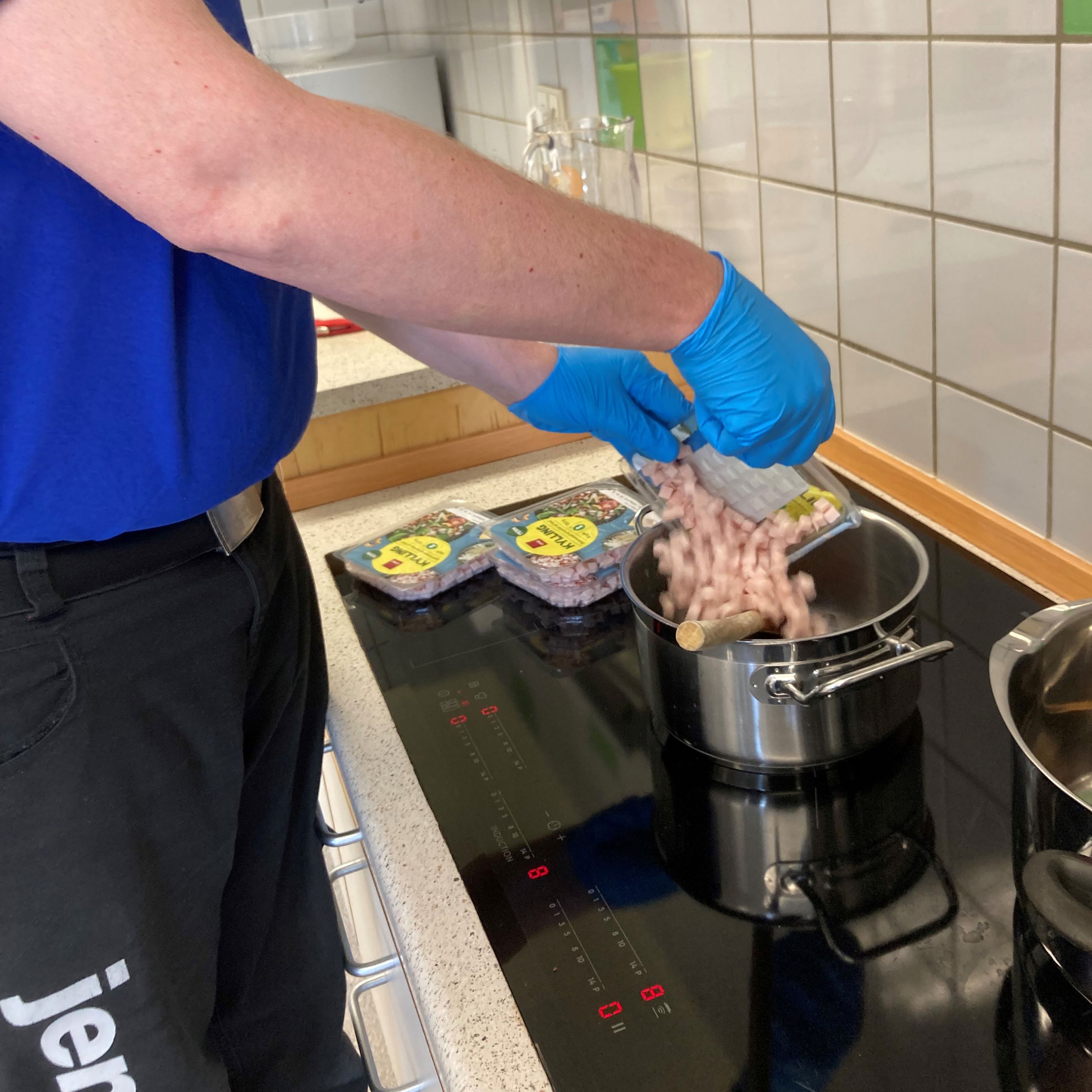 En borger er ved at åben nogle pakker med kød og putte dem i en gryde.