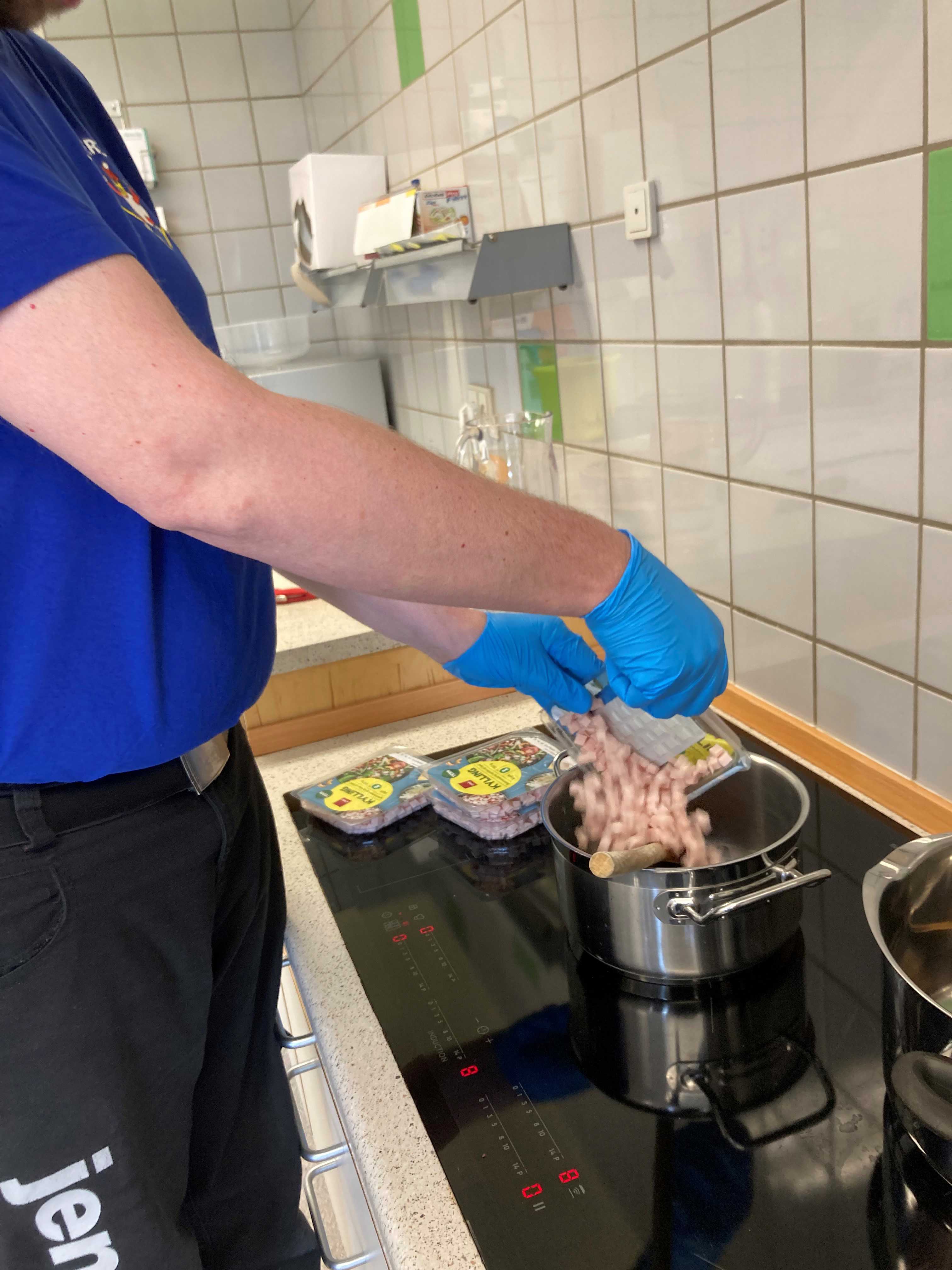 En borger er ved at åben nogle pakker med kød og putte dem i en gryde.