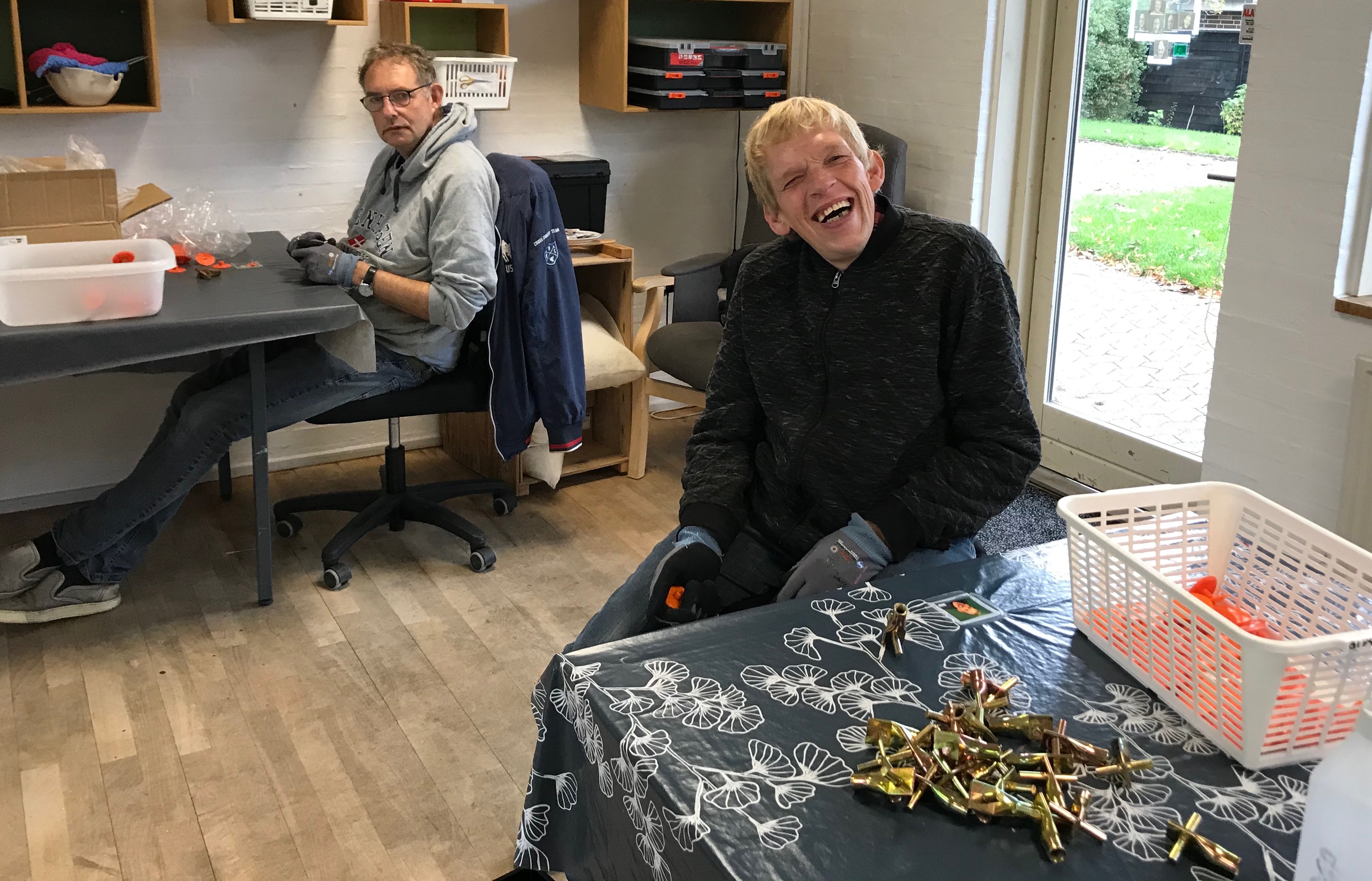 To borger i gang med og samle små plastting og den ene smiler da han ser der bliver taget et billede af dem