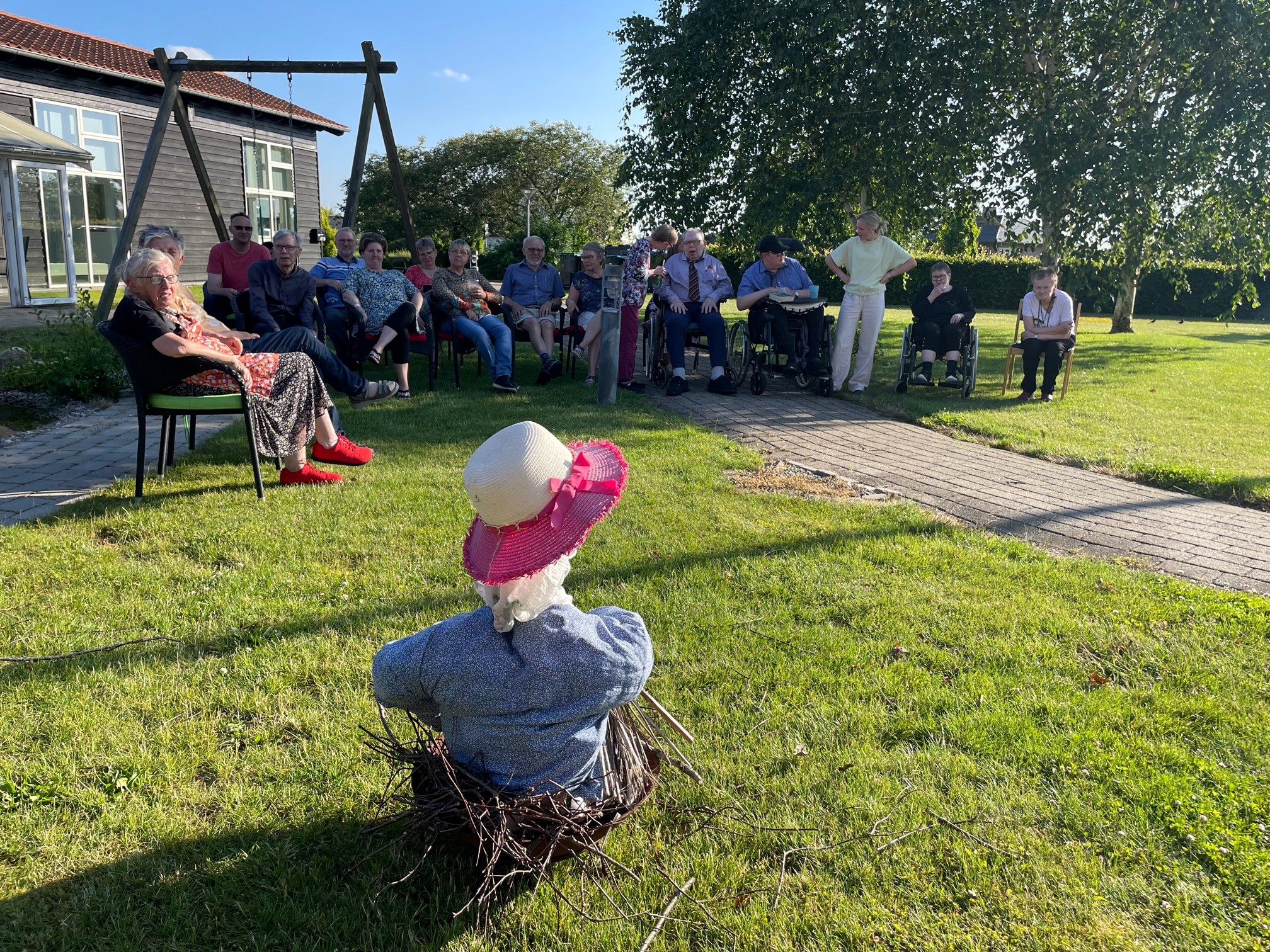 Man ser ryggen af heksen, der sidder i en kurv og kigger ud på borgerne, de kigger tilbage