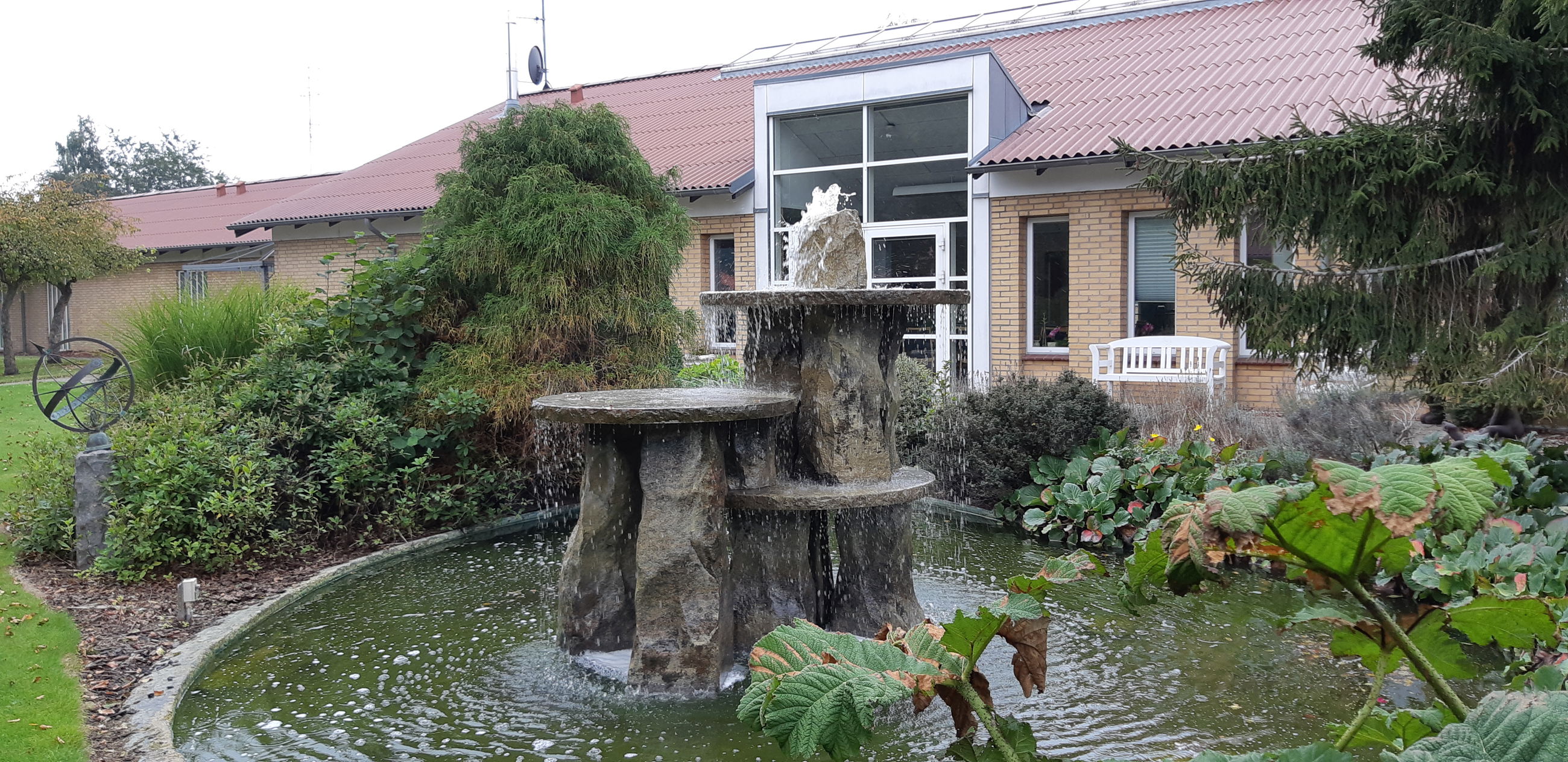 Springvandet ude i haven hvor bygningen af Solengården er i baggrunden.