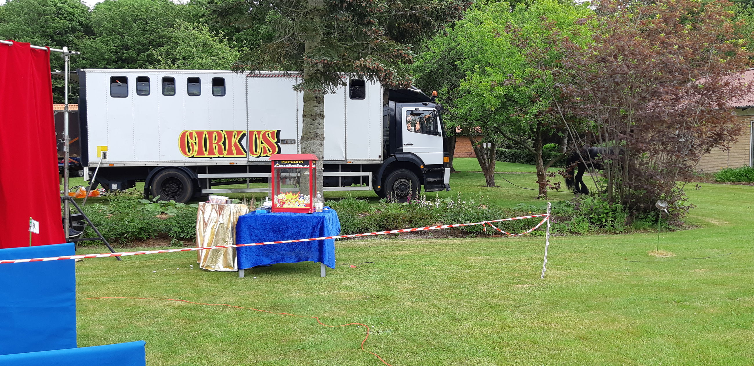 Cirkusvogne og popcorn maskine er stillet op i haven
