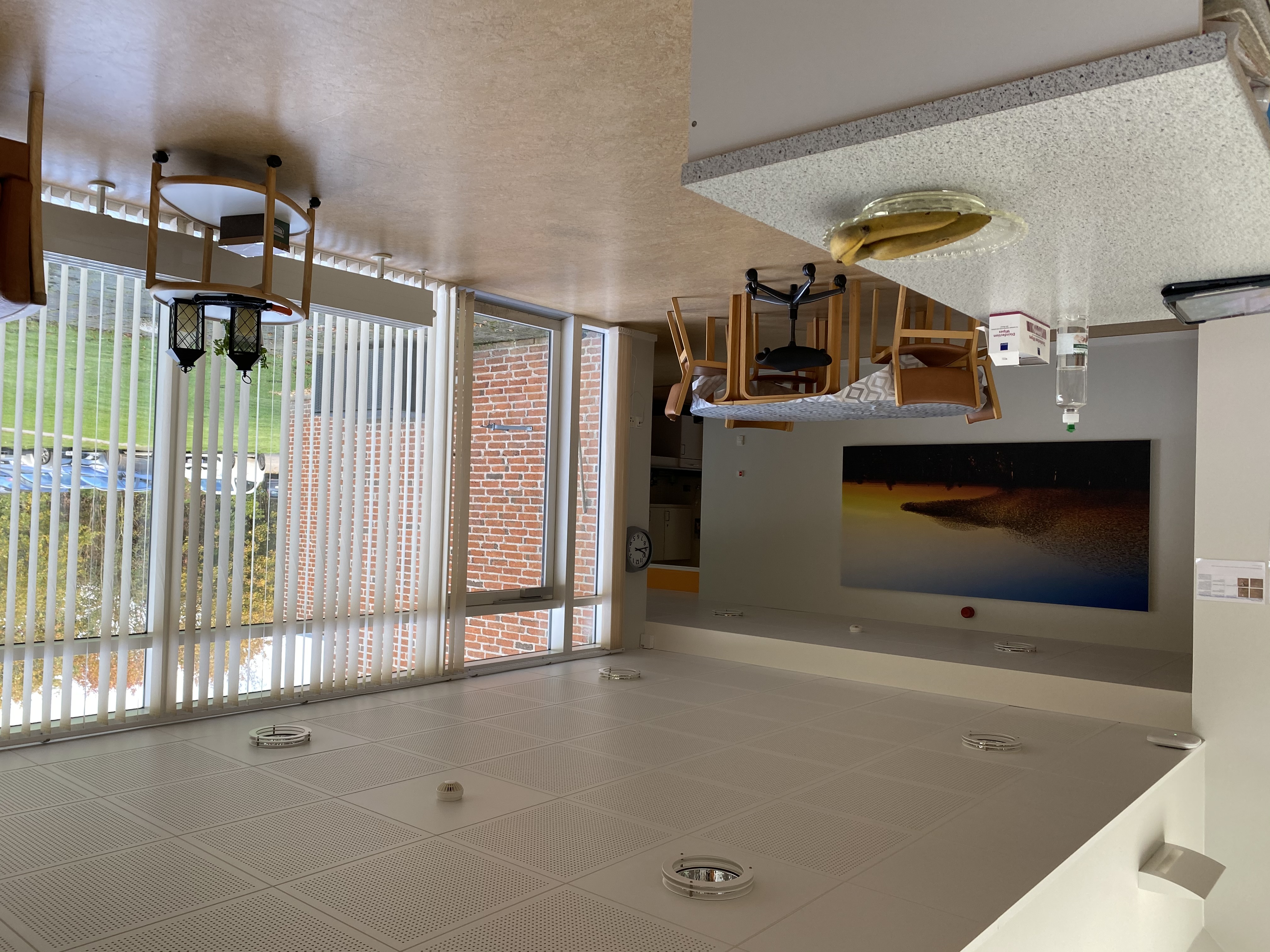 I opholdstuen er der et rundt bord med fire stole med rygløn og en stol med hjul. Henne ved det store vinduesparti er der et lille rullebord med nogle lanterner på.