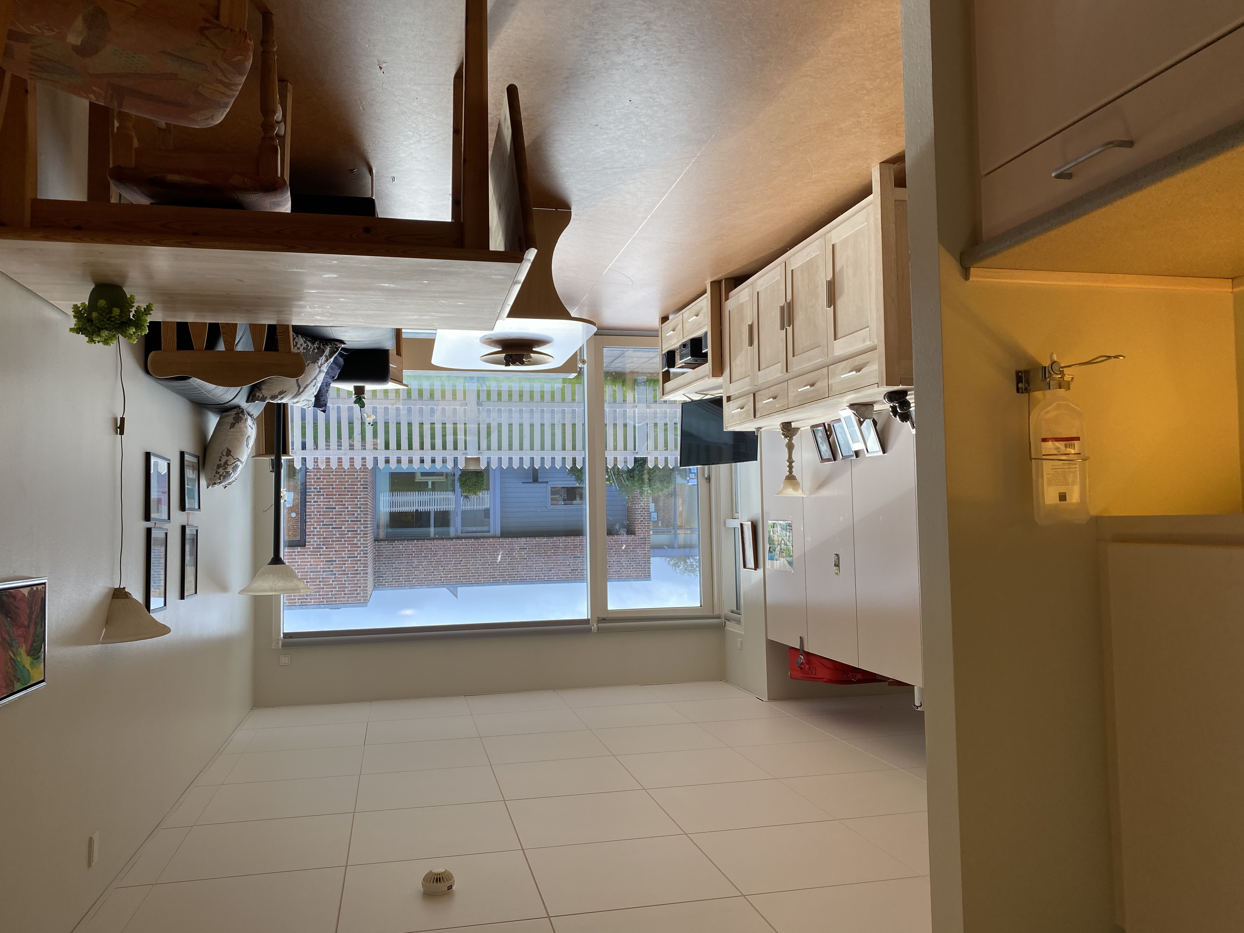 Inde i en borgers lejlighed er der en sofa og et sofabord. I lejligheden der en skænk og et tv bord. I lejligheden er der også et spisebord og et lille thekøkken. 