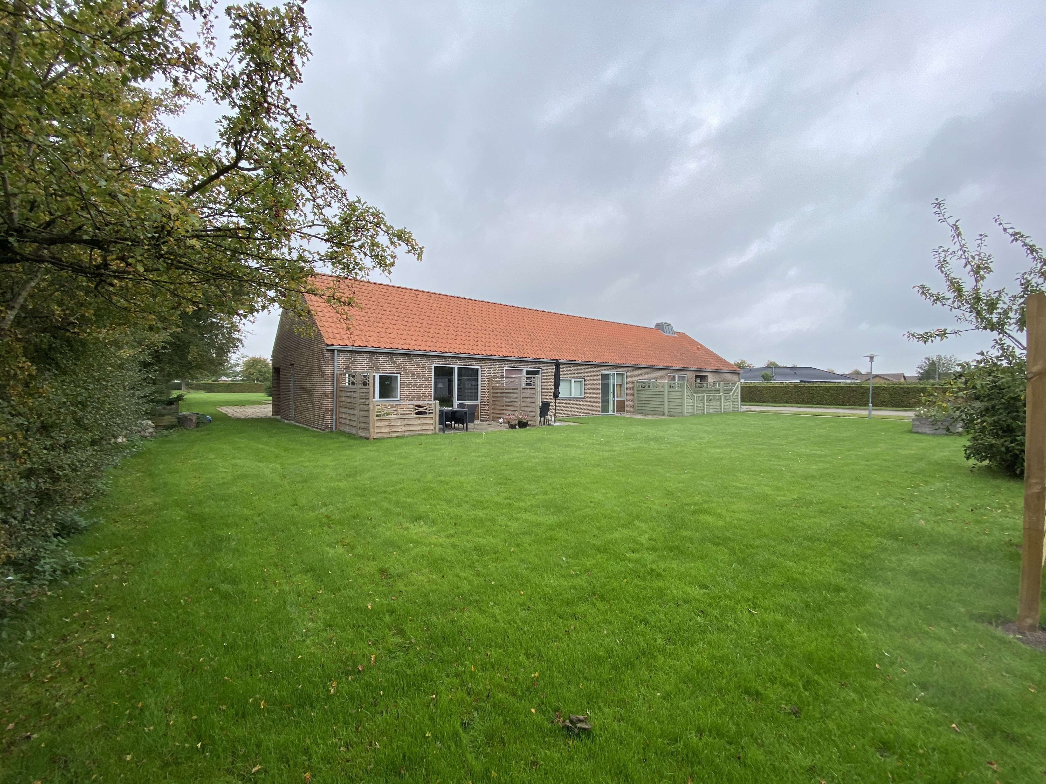 Ulriksallé bagved. Der ligger en stor grøn græsplæne der grænser på til bygningerne. Bygninger er røde mursten, og der er rødt tegltag på.