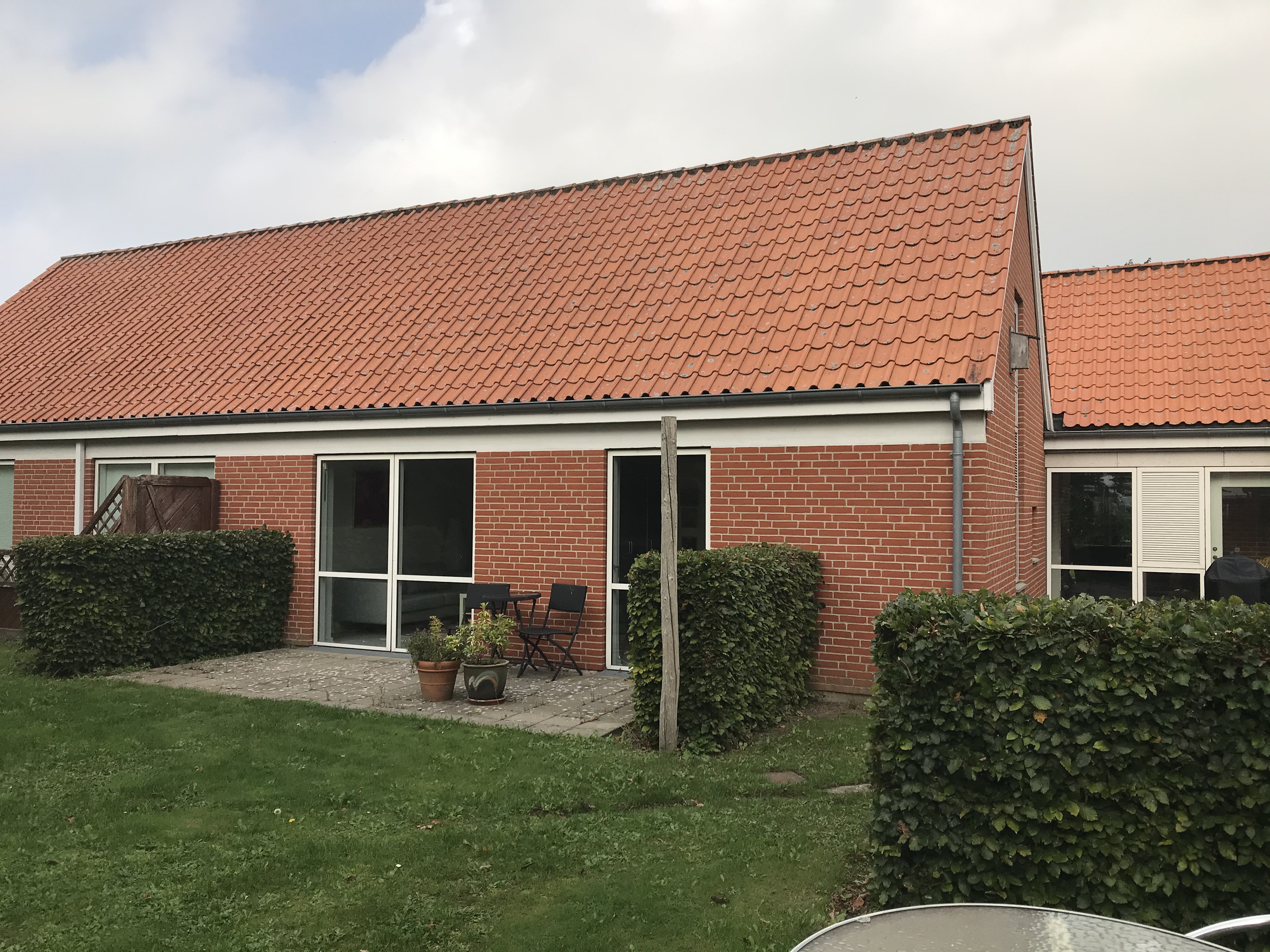 Rød bygning på Lærkely, terasse, græs og grønne buske