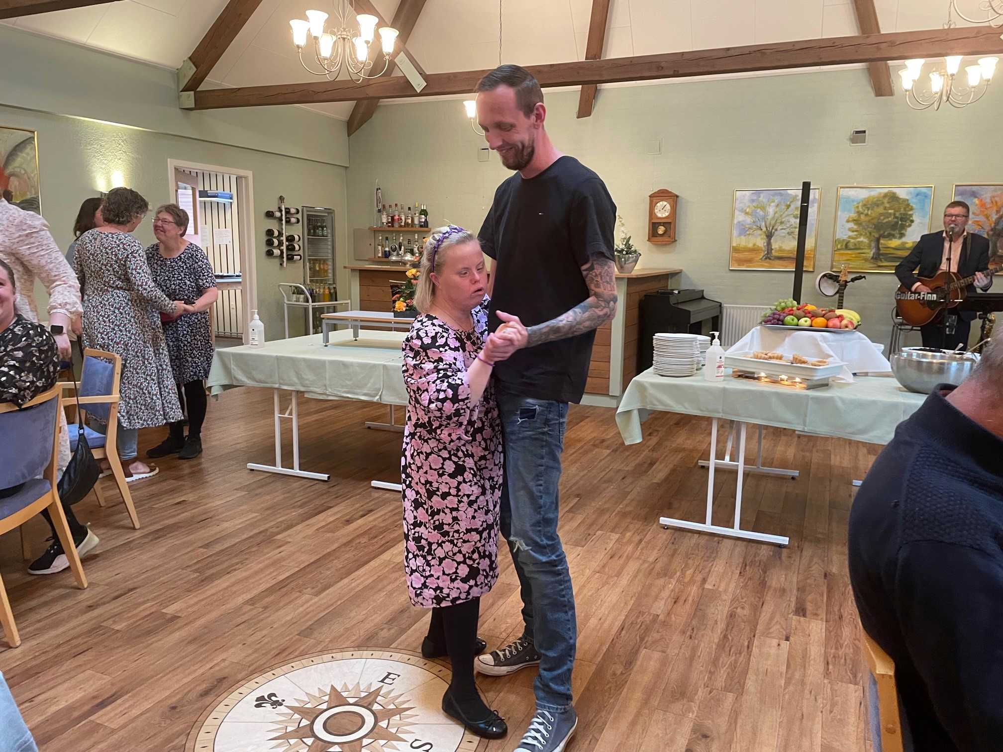 To borgere danser sammen på dansegulvet, i baggrunden ser man Giutar Finn spille